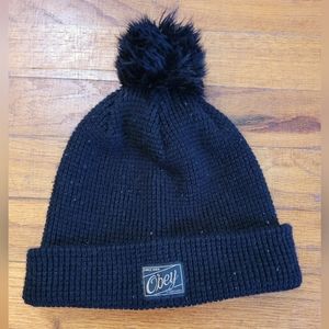 Black OBEY beanie with faux fur pompom.